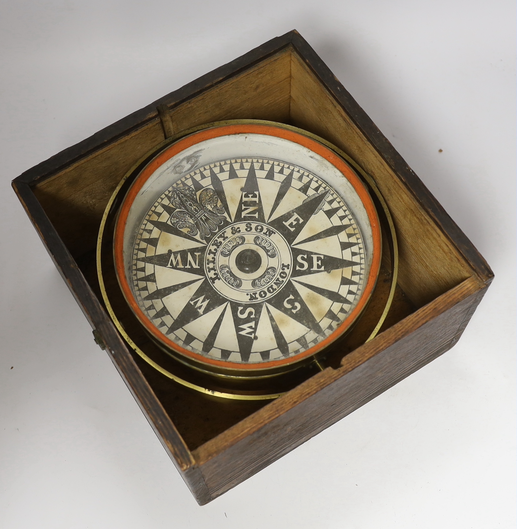 A pine cased, brass bodied compass on a gimbal, with applied paper face signed ‘Lilley & Son London’, 26cm wide, 26cm deep, 16cm high